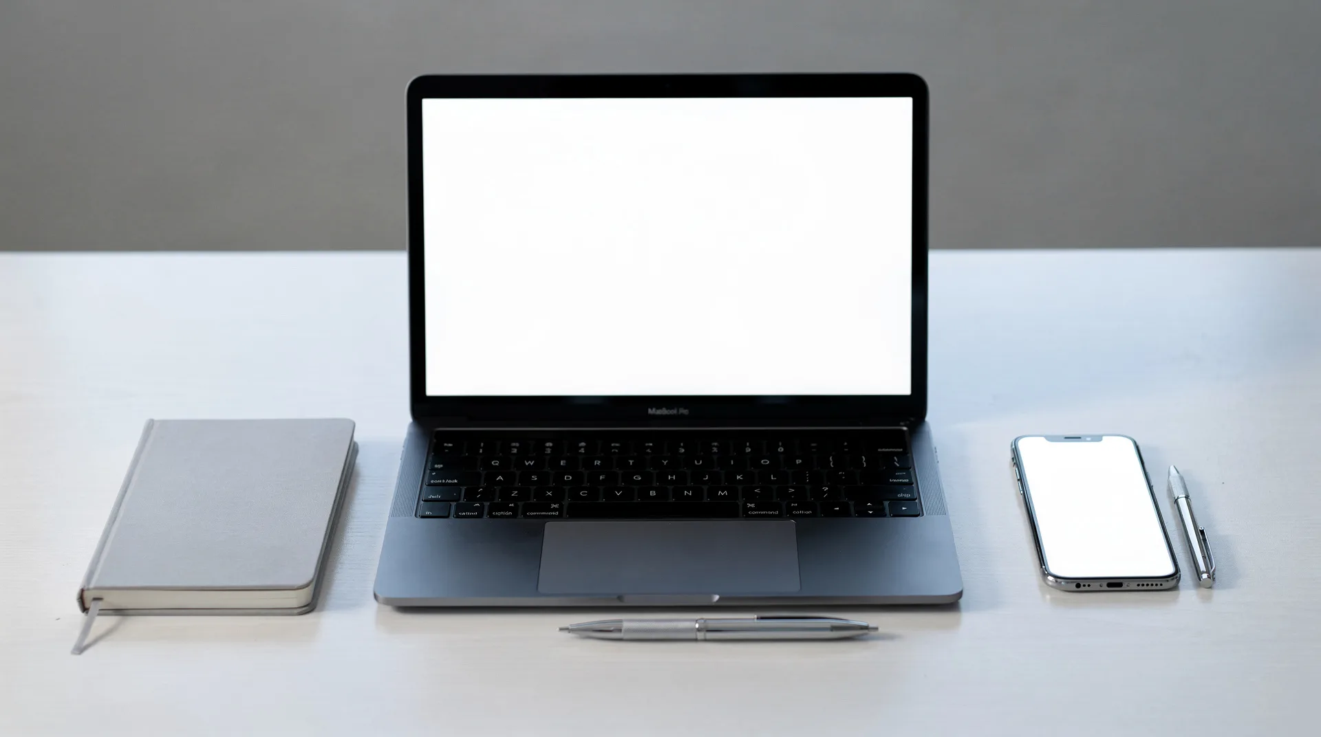 Portátil y smartphone sobre un escritorio minimalista con un cuaderno, concepto de banca online